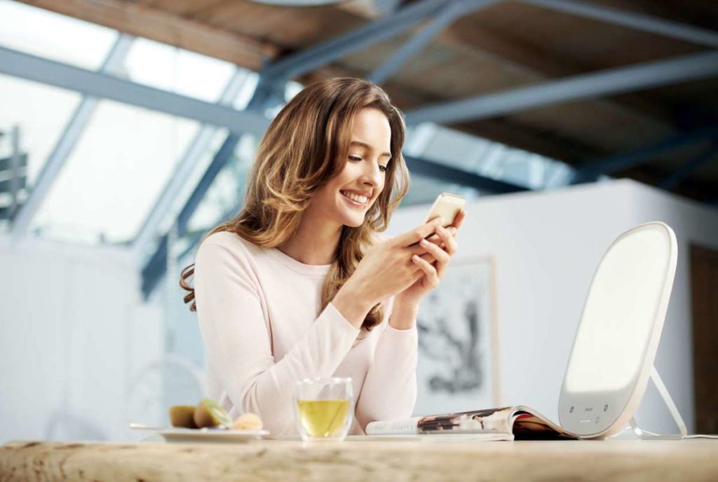 Femme qui prend sont petit-déjeuner et qui fait de la luminothérapie